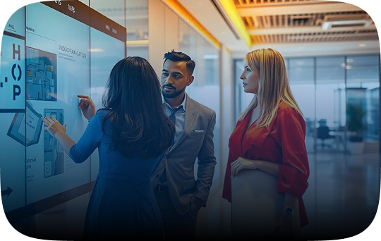 Three individuals collaborate, focused on a large screen, showcasing teamwork.